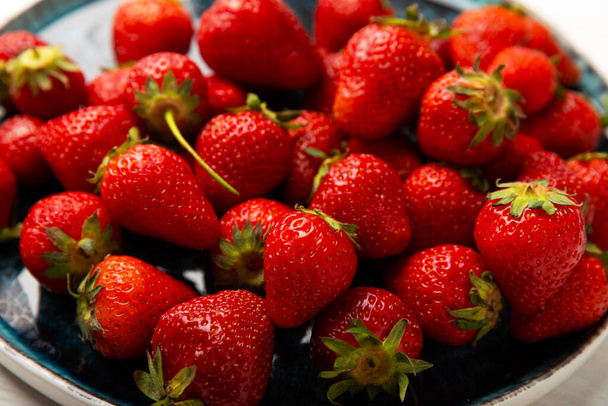 Frische reife Erdbeeren in einem Teller auf weißem Holzhintergrund.Vegetarische Bio-Beeren.Gesundes Lebensmittel.Vitamin.Kopierplatz.Platz für Text - Foto, Bild