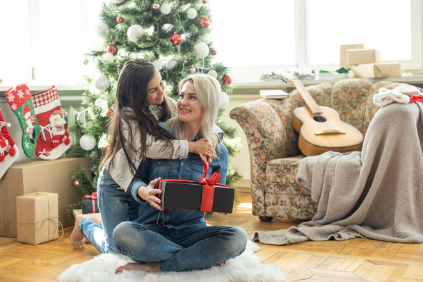 Mother with her child daughter celebrating near Christmas tree. - Photo, Image