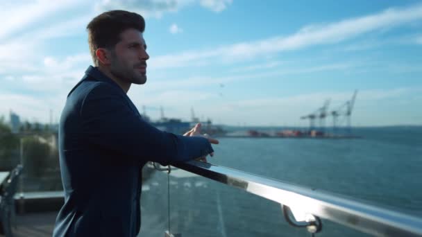 Confident businessman rest balcony in morning sunlight at sea port cranes view. Serious businessman relaxing taking break on glass cafe terrace. Attractive guy professional waiting client meeting. - Metraje, vídeo