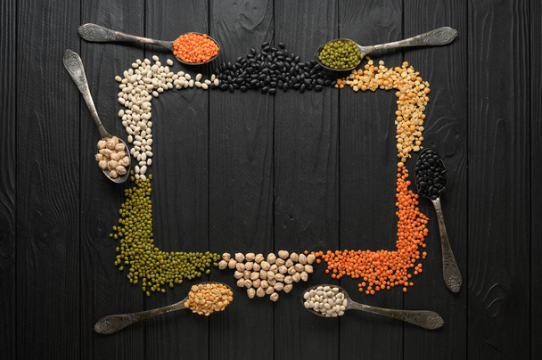 Legumes, overhead flat lay shot on a dark rustic wooden background with a place for text - Zdjęcie, obraz