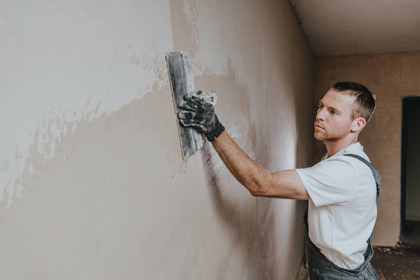 工事中の男性建築家は、建設用のトロールを使用して壁を漆喰全体にわたっています。テキストのための空白のスペースと水平パノラマバナー. - 写真・画像