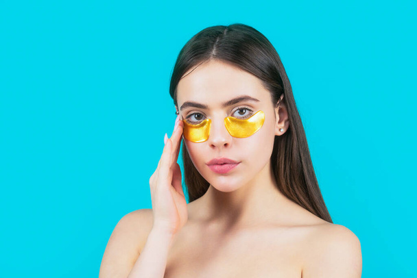 Eyes mask cosmetic patches woman face closeup. Woman applying golden eye patches. Close up portrait girl. Portrait of beauty woman with eye patches showing an effect of perfect skin. - Photo, Image