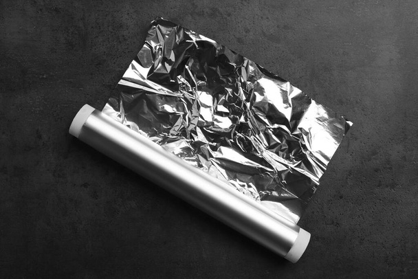 Roll of aluminum foil on dark grey table, top view - Φωτογραφία, εικόνα