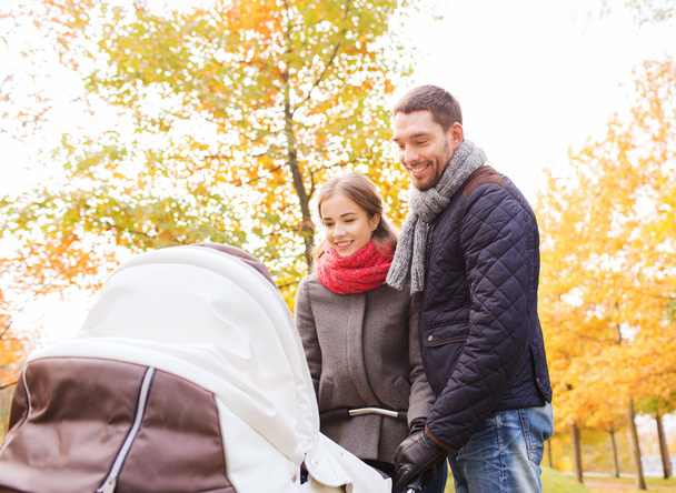 smiling couple with baby pram in autumn park - Фото, изображение