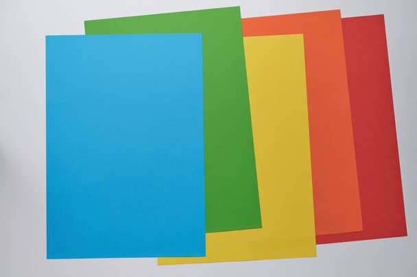 Zdjęcie tło pięciu arkuszy w różnych kolorach leżą na siebie, górny papier jest niebieski, tekst wolne miejsce - Zdjęcie, obraz