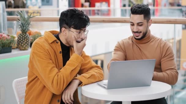 Young excited arab guy shows new project on laptop shocked man reading great news applauds support friend admires excellent result achievement expresses his opinion happy friends celebrating success - Metraje, vídeo