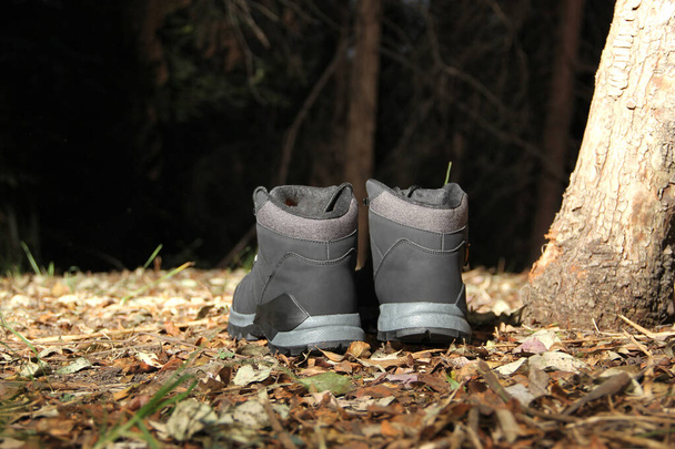 Black boots in the dark forest between trees ready for hiking in the mountains to explore at night - Photo, image