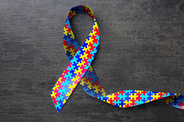 World Autism Awareness Day. Colorful puzzle ribbon on grey stone background, top view - Foto, immagini
