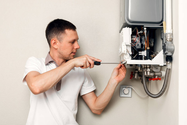 A plumber is attempting to fix a residential heating problem. Gas boiler repair - Fotoğraf, Görsel