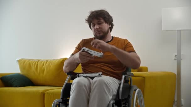 A man in a wheelchair holding guns and pulls back the shutter. Mid shot - Filmagem, Vídeo