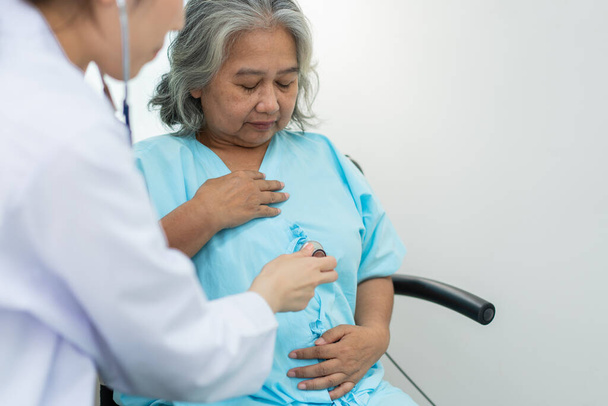 Artsen onderzoeken hart met een stethoscoop en praten met een oudere vrouw in een kliniek voor controle jaarlijkse controle, Geneeskundige gezondheidszorg en ziektekostenverzekering concept. - Foto, afbeelding