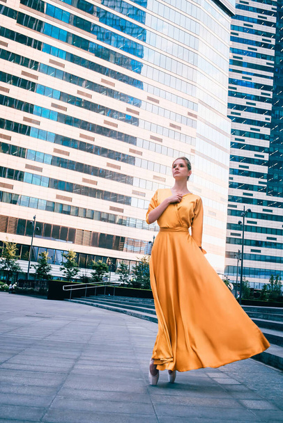 Ballerina, ballet dancer in yellow gown, dancing on the city street.	 - Foto, afbeelding