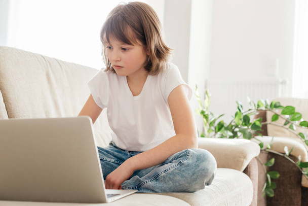 Mesafe öğrenme. İnternette okuyan kız öğrenci ya da internetten bilgisayar kullanarak iletişim kuran. Çevrimiçi evde eğitim gören çocuklar kavramı - Fotoğraf, Görsel