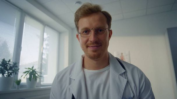 Pov video yakışıklı Avrupalı doktor sağlık kliniğindeki hastaya danışmanlık yapıyor. Gülümseyen doktor hastane ofisinde tıbbi tavsiye veriyor. Modern işyerinde çalışan genç bir tıp uzmanı.. - Fotoğraf, Görsel