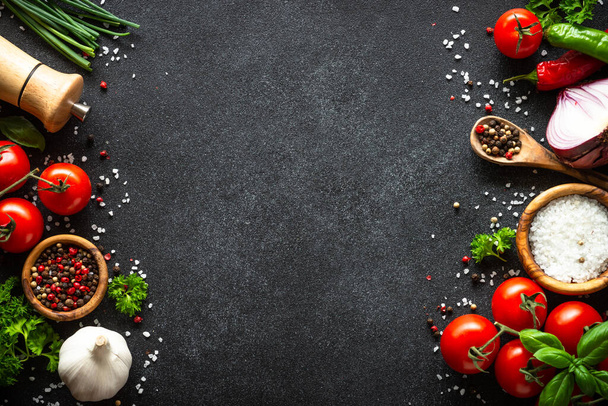 Food background on black stone table. Fresh vegetables, herbs and spices. Ingredients for cooking with copy space. - Фото, зображення