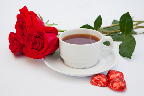 Buquê de rosas vermelhas ao lado de uma xícara de chá
 - Foto, Imagem