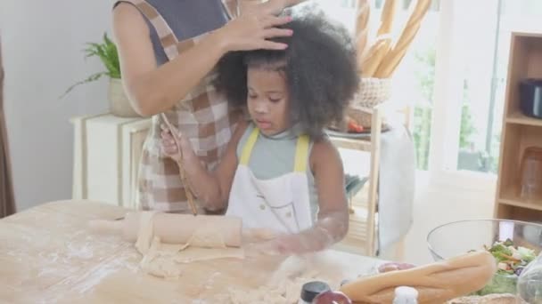 African America Familie mit Mutter in Schürze Dreschmehl zum Kochen mit Tochter zu Hause in der Küche, Eltern und kleines Kind bereiten Essen mit Spaß und spielerisch. - Filmmaterial, Video