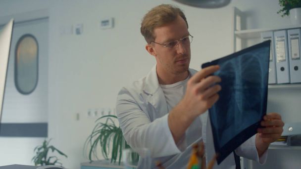 Médecin diagnostiquant en ligne vérifier poumons radiographie de près. Thérapeute européen utilisant l'ordinateur moderne sur la consultation médicale. Homme sérieux médecin examinant le patient à distance en cas de pandémie de coronavirus. - Photo, image