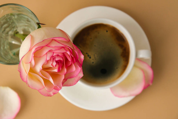 Rosa tierna sobre jarrón con taza de café blanco sobre fondo beige. Composición mínima. Romántica flor rosa pastel. Estética moderna. Tonos neutros de tierra. Desayuno de vacaciones por la mañana Creativo - Foto, imagen