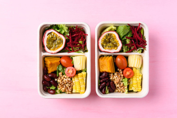 Čerstvý zeleninový salát v biologicky rozložitelné misky na růžovém pozadí, zdravé veganské jídlo - Fotografie, Obrázek
