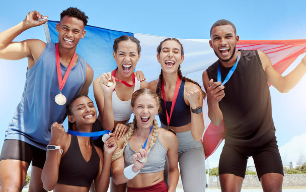 Счастливые и гордые французские олимпийские спортсмены празднуют завоевание медалей для своей страны. Портрет разноплановой группы спортивных людей с французским флагом, аплодирующих и гордящихся своим успехом и победой. - Фото, изображение