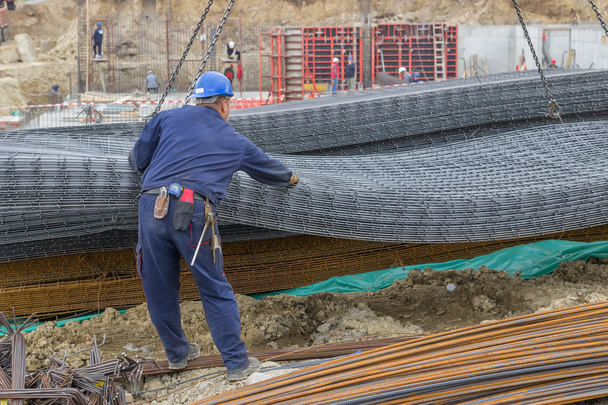 Eisenarbeiter entladen Bewehrungsstahl vom Kran für den Bau - Foto, Bild