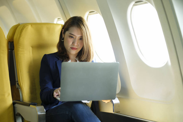 Молода бізнес-леді У літаку, що використовує ноутбук під час польоту на літаку, концепція подорожей
. - Фото, зображення