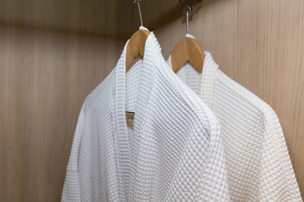 white bathrobes hanging in wooden closet - Photo, Image