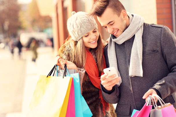 Happy couple faisant du shopping en ville avec smartphone
 - Photo, image
