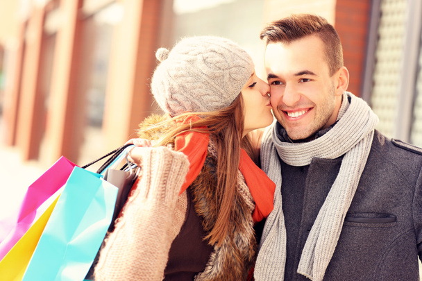 Mujer feliz besando a un hombre mientras va de compras
 - Foto, Imagen