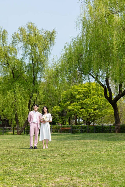 Beautiful Asian couple at wedding photoshoot in the park  - Fotó, kép