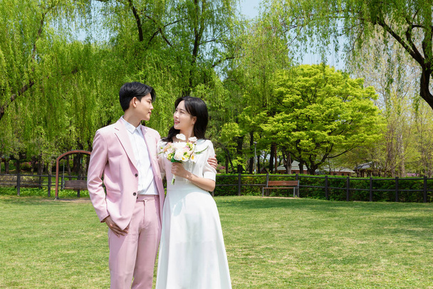Beautiful Asian couple at wedding photoshoot in the park  - Фото, изображение