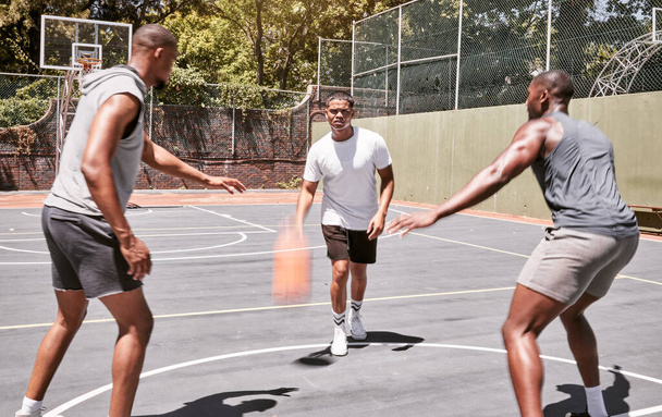 Drie Afro-Amerikaanse mannen die basketbal spelen op een veld buiten. Zwarte man en zijn sportieve vrienden die buiten atletisch zijn. Groep basketballers concurreren in een wedstrijd of spel voor recreatie plezier. - Foto, afbeelding