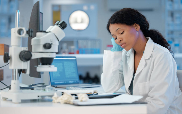 Shot van een jonge vrouw op zoek verveeld terwijl op het werk in haar lab. - Foto, afbeelding