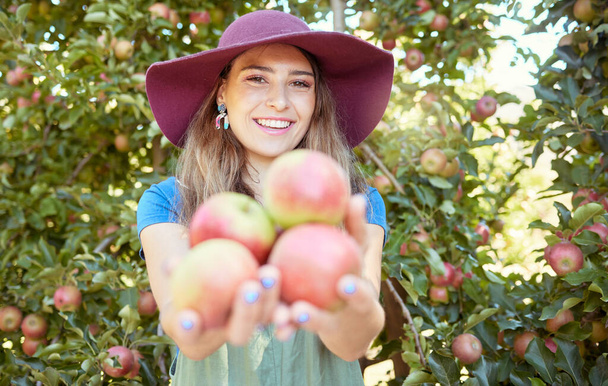 Porträt einer glücklichen jungen Frau, die an sonnigen Tagen frisch gepflücktes Rot von Bäumen auf nachhaltigem Obstbaumland im Freien hält. Landwirt erntet saftige, nahrhafte Bio-Früchte in der Saison. - Foto, Bild