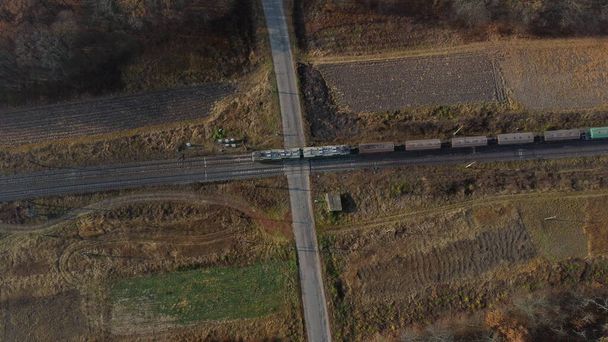 Top View tavarajuna kulkee Railway Crossing. Aerial Drone View Flight Over risteys Railway Tracks ja Asfaltti Road. Kuljetus, Rautatierahti, Toimitus. Rautatievaunujen ajaminen rautateillä. - Valokuva, kuva