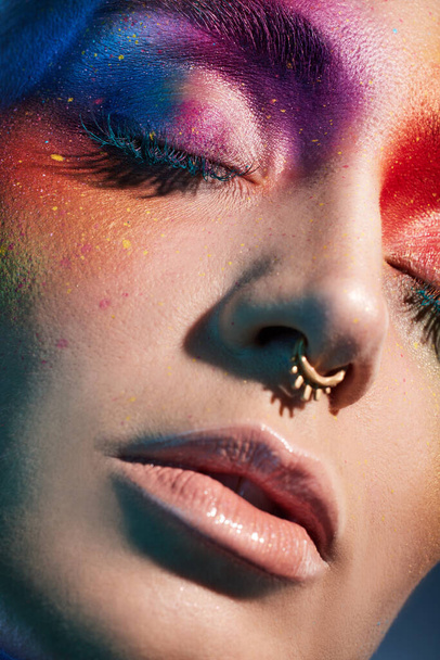 Studio girato di una giovane donna in posa con vernice multicolore sul viso. - Foto, immagini