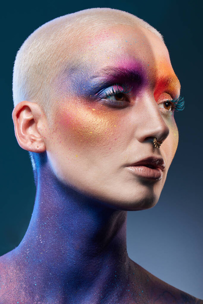 Studio shot van een jonge vrouw poseren met multi-gekleurde verf op haar gezicht. - Foto, afbeelding
