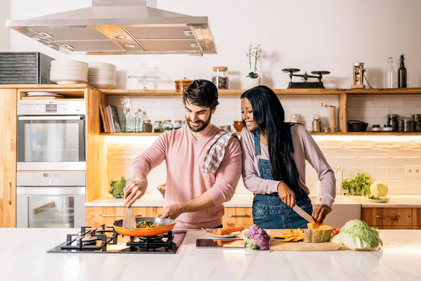 Cute multi-ethnic couple preparing lunch together in the kitchen at home. - Foto, Imagem