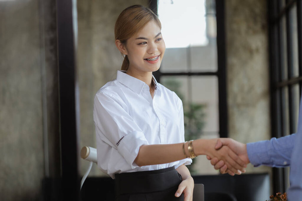 Le donne asiatiche stanno stringendo la mano con partner commerciali, giovani ed energiche donne d'affari asiatiche che formano una moderna società di startup manageriale. Il concetto di leader femminili che gestiscono un'impresa. - Foto, immagini
