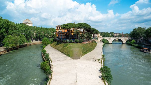 View of The Tiber Island in Rome, Italy. Island surrounded by Tiber river with resting people, old buildings and greenery - Foto, Imagem