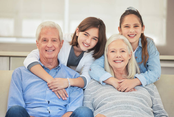 Съемка взрослой пары, сближающейся со своими внуками на диване дома. - Фото, изображение
