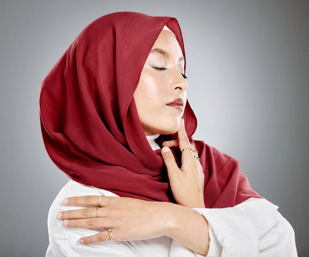 Beautiful muslim woman posing in studio wearing hijab. Headshot of stunning confident arab model standing against grey background. Fashionable woman wearing a headscarf. Elegant female in a headwrap. - Фото, зображення
