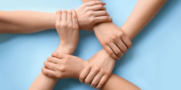 People holding hands together on light blue background, top view - 写真・画像
