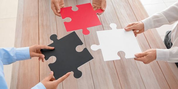 Business team with pieces of puzzle at wooden table - Foto, imagen