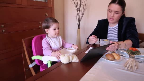 Ευτυχισμένο μωρό κορίτσι τρώει και βλέποντας ηλεκτρονική ταμπλέτα - Πλάνα, βίντεο