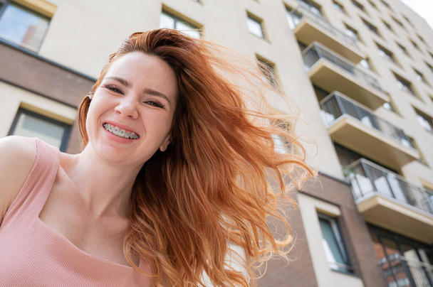 Beautiful young red-haired woman with braces on her teeth smiling in the summer outdoors. - Foto, Bild