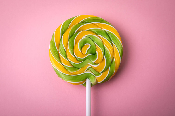 Round spiral candy on a stick. Pink background. - Zdjęcie, obraz