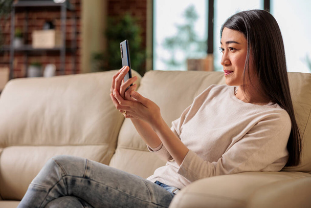 Alkalmi autentikus megjelenés boldog ázsiai nő használ okostelefon otthon, web internet technológia okostelefon felhasználó mobil üzenet szociális média kommunikáció digitális eszköz - Fotó, kép