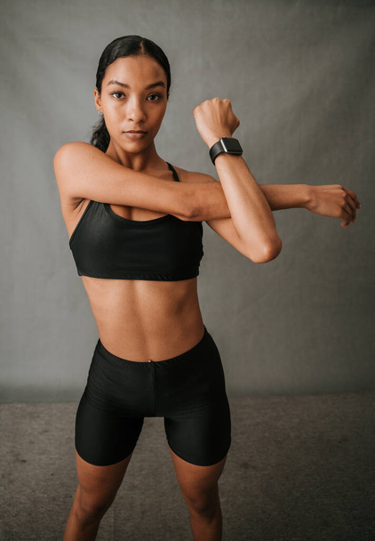 Lähikuva Afrikkalainen Amerikkalainen tekee käsivarren venyttely liikunta näköinen keskittynyt hänen urheiluvaatteet ja wearingwatch studiossa Laadukas kuva - Valokuva, kuva